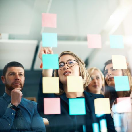 four business people reviewing post-it notes flow chart arranged on window