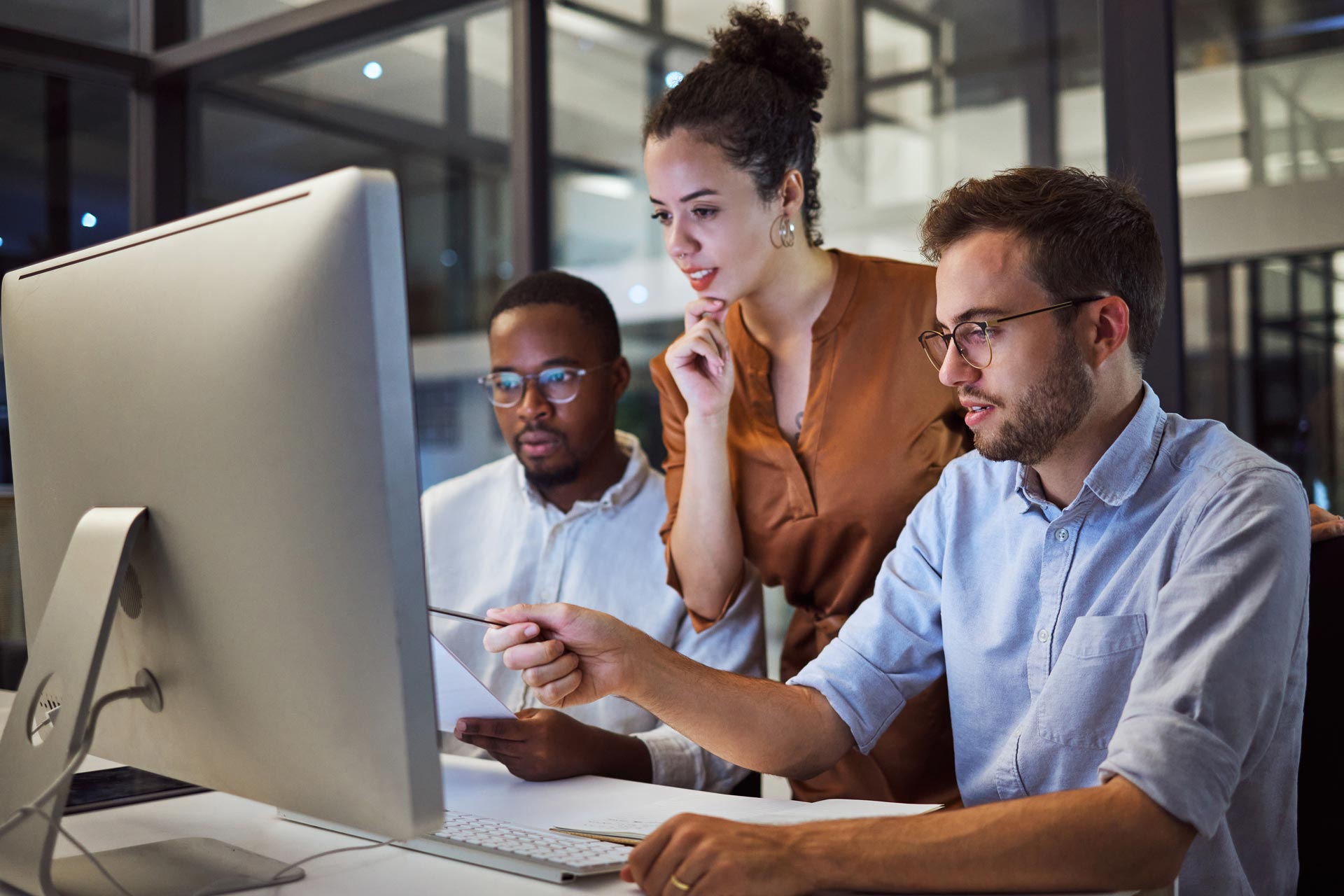 three business people looking at desktop computer screen together